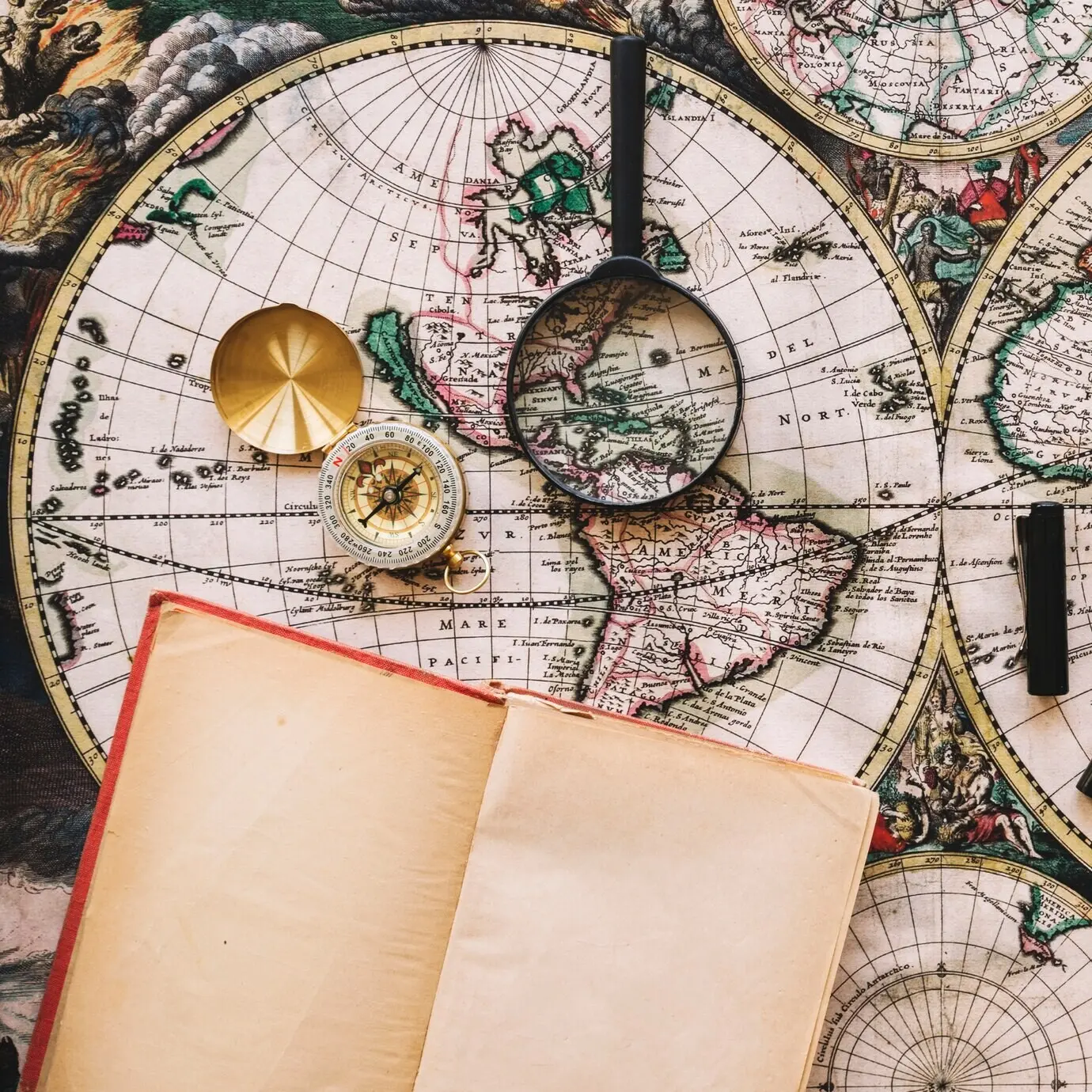 Kompass und Lupe in der Nähe eines geöffneten Notizbuchs.